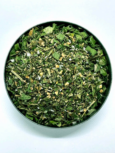 Top view of a small bowl of green goddess dressing mix with green onions and herbs
