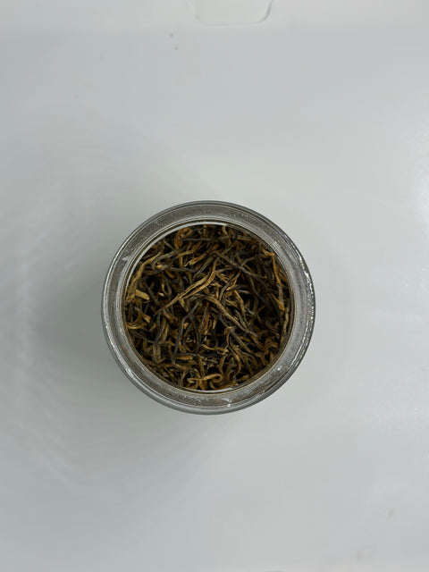 Small dish with loose pile of golden needles loose leaf tea